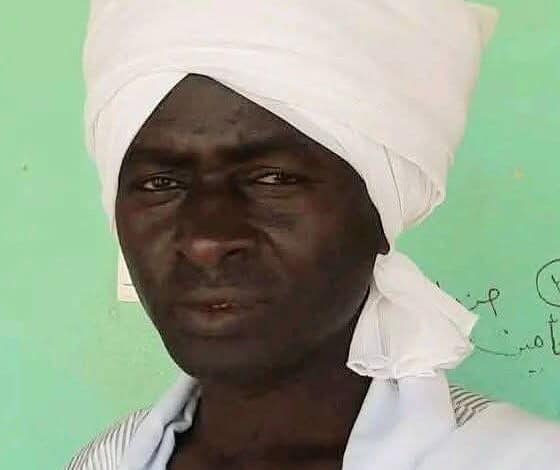 رجل سوداني يرتدي ملابس تقليدية وتاج أبيض، يُظهر ملامح وجهه في صورة واضحة، مع خلفية خضراء تتضمن رسومات وخطوط يدوية.